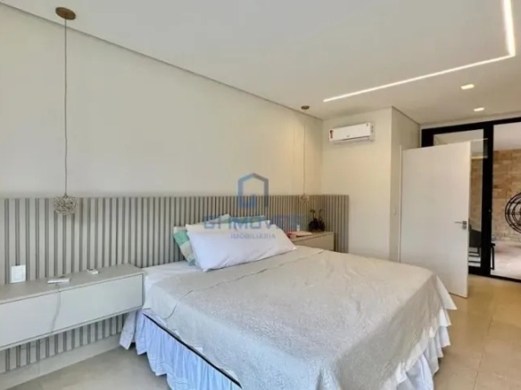 Suíte master com cabeceira de madeira e iluminação embutida no condomínio Aldeia do Vale.