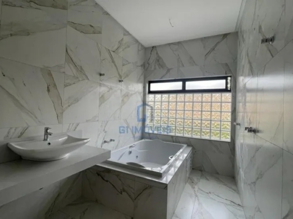 Banheiro da suíte máster no Aldeia do Vale com revestimento marmorizado e banheira de hidromassagem instalada.