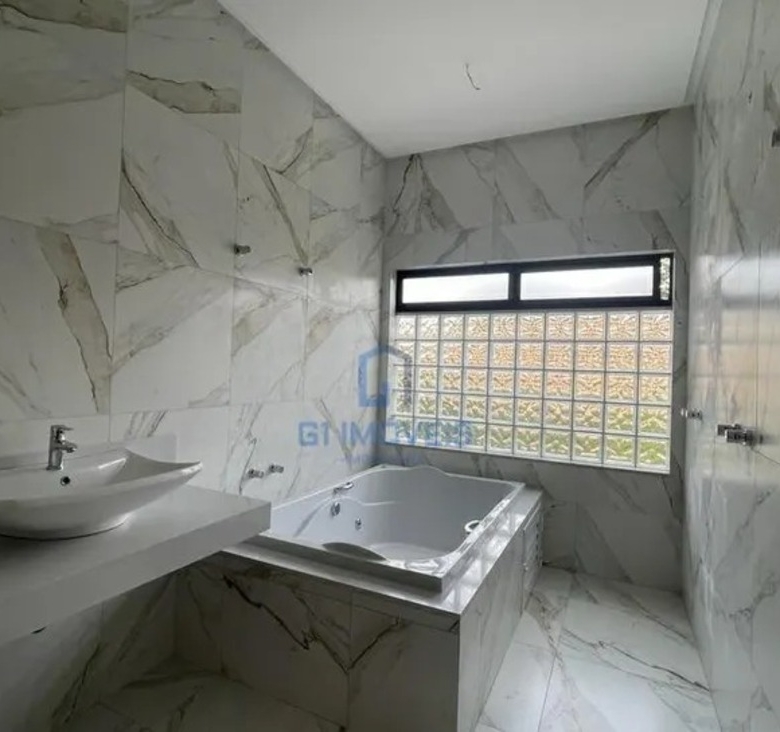 Banheiro da suíte máster no Aldeia do Vale com revestimento marmorizado e banheira de hidromassagem instalada.