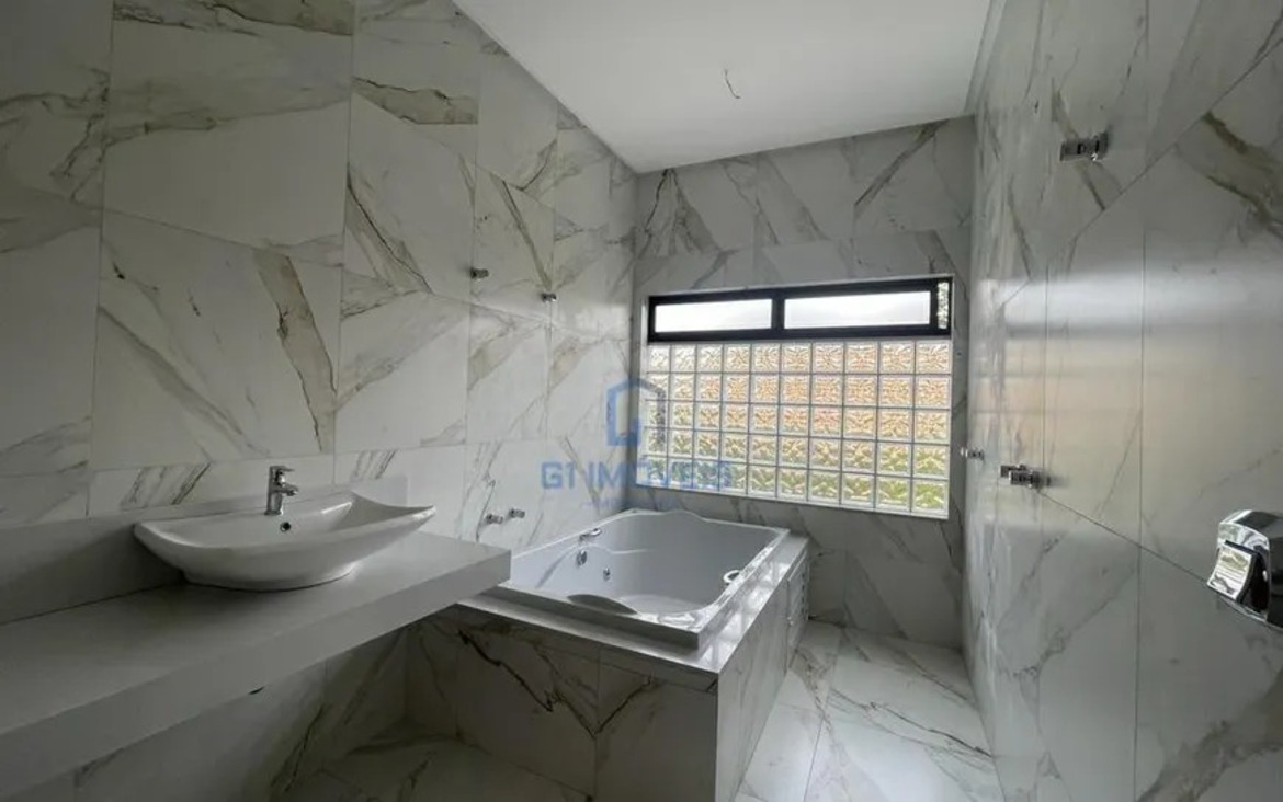 Banheiro da suíte máster no Aldeia do Vale com revestimento marmorizado e banheira de hidromassagem instalada.