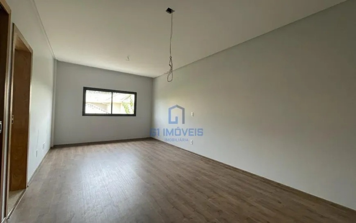 Suíte plena com paredes brancas e piso amadeirado, pronta para personalização de armários.