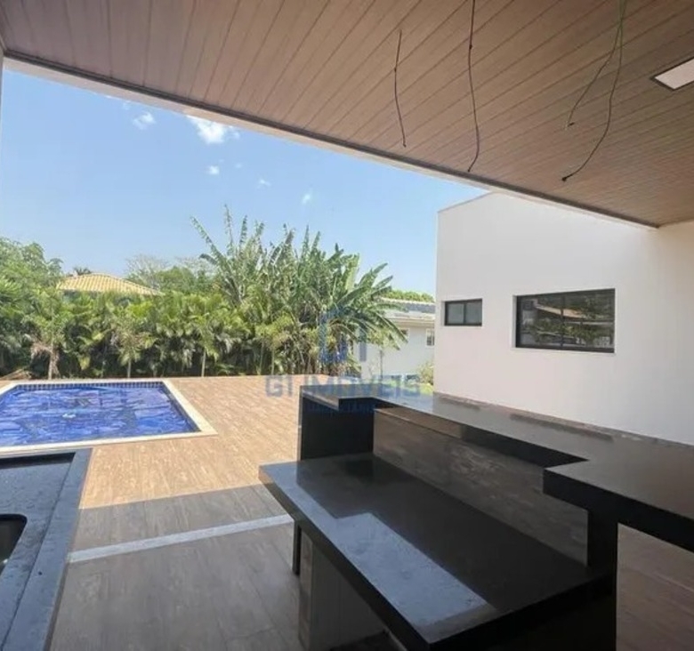Área gourmet integrada com bancada em granito escuro e vista para a área de lazer externa.