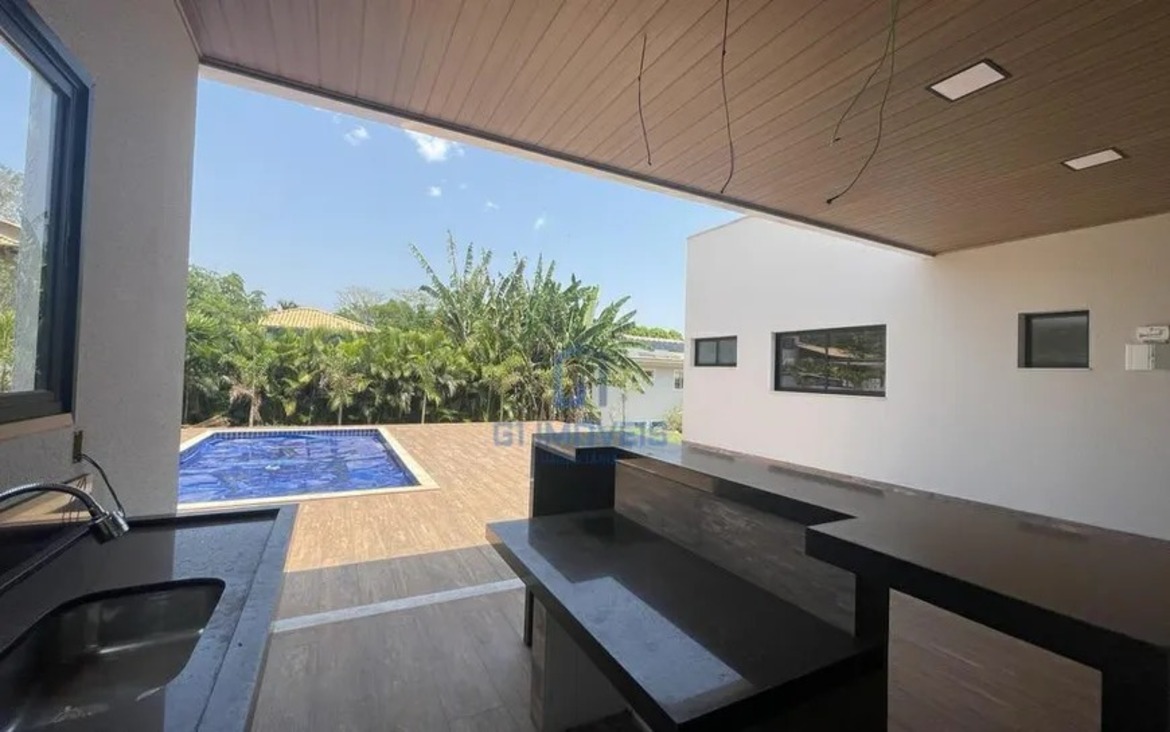 Área gourmet integrada com bancada em granito escuro e vista para a área de lazer externa.