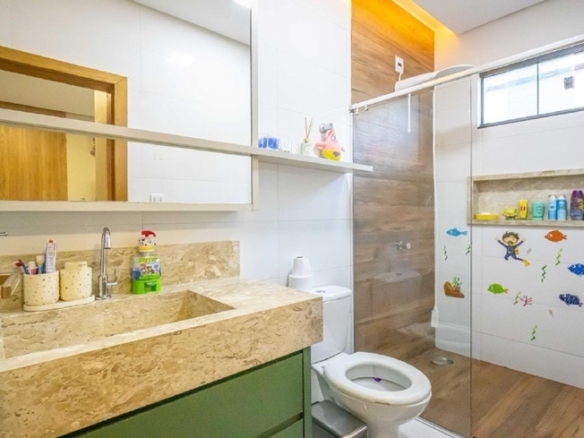 Banheiro infantil com gabinete verde, prateleiras e decoração colorida