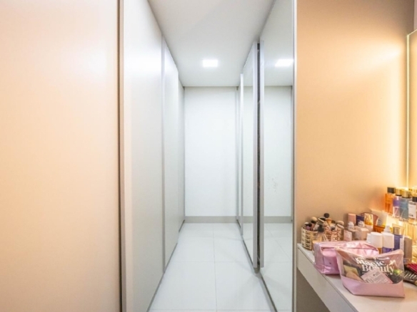 Closet planejado com armários de vidro e penteadeira iluminada