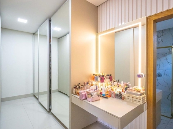 Closet planejado com armários de vidro e penteadeira iluminada