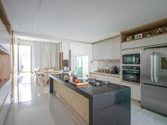 Cozinha espaçosa com ilha, armários brancos e eletrodomésticos