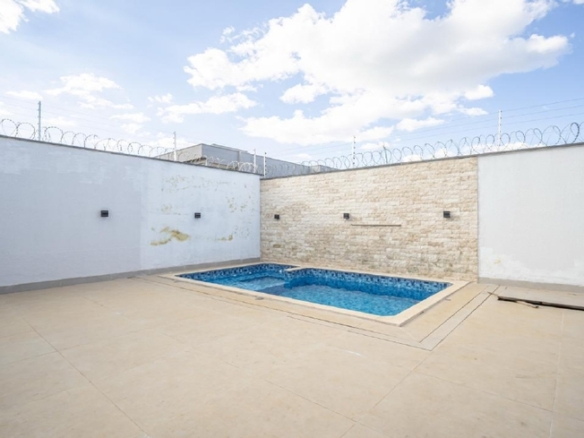 Piscina pequena em quintal amplo com muro branco