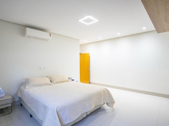 Quarto de casal amplo com cama branca e iluminação embutida