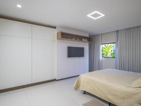 Quarto de casal com cama, painel cinza e armários planejados