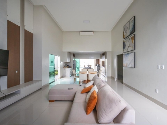 Sala de estar ampla com sofá branco e corredor ao fundo