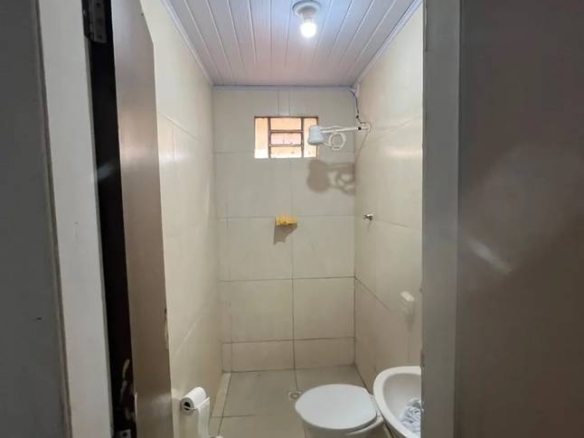Banheiro com pia, vaso sanitário e bancada, além de iluminação embutida e revestimento de madeira no Casa com ponto comercial no Parque Amazônia