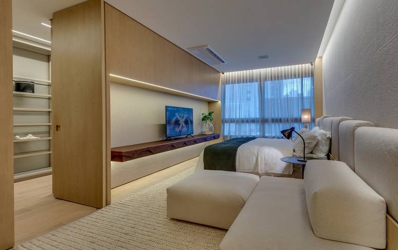 Sala de estar com sofá e televisão, além de iluminação embutida