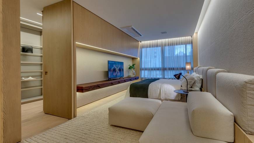 Sala de estar com sofá e televisão, além de iluminação embutida