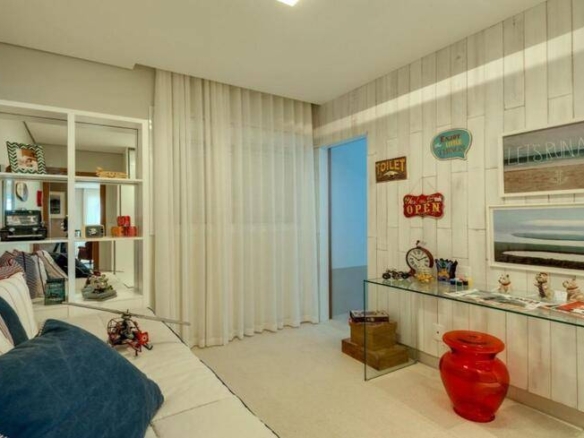 Sala de estar com painel de televisão e cadeiras, além de iluminação embutida