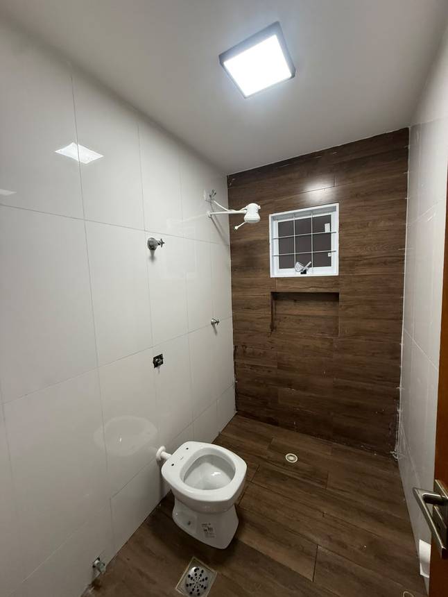 Banheiro com pia e vaso sanitário, além de iluminação embutida