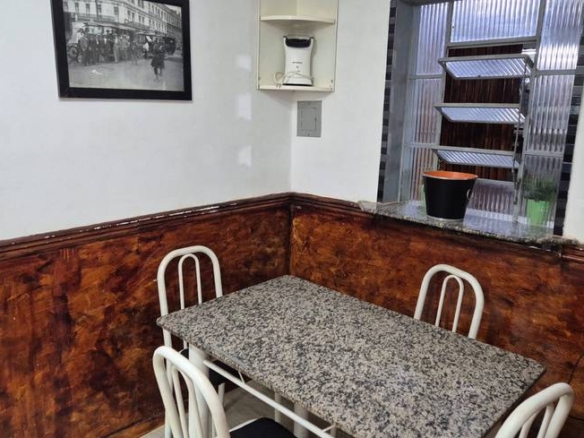 Sala de estar com mesa e cadeiras, além de iluminação embutida e revestimento claro