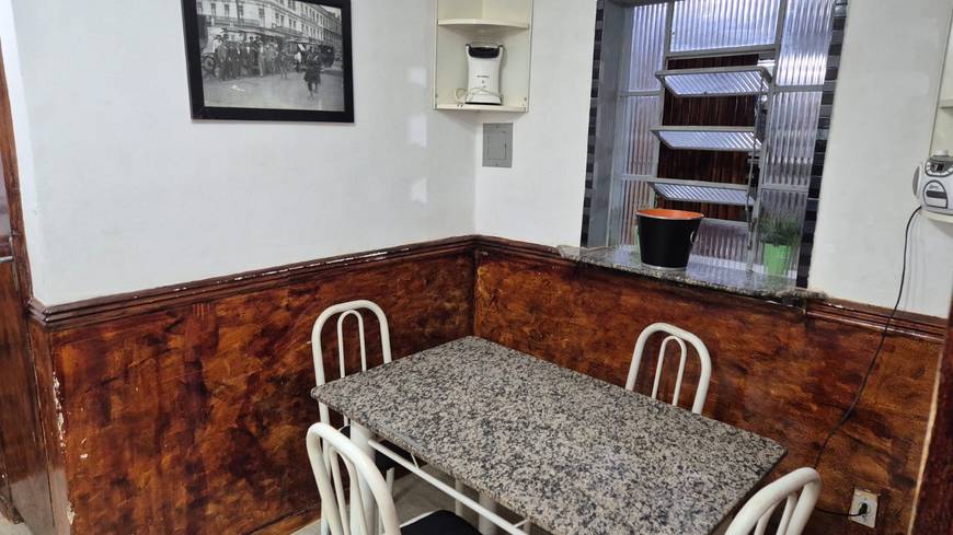 Sala de estar com mesa e cadeiras, além de iluminação embutida e revestimento claro