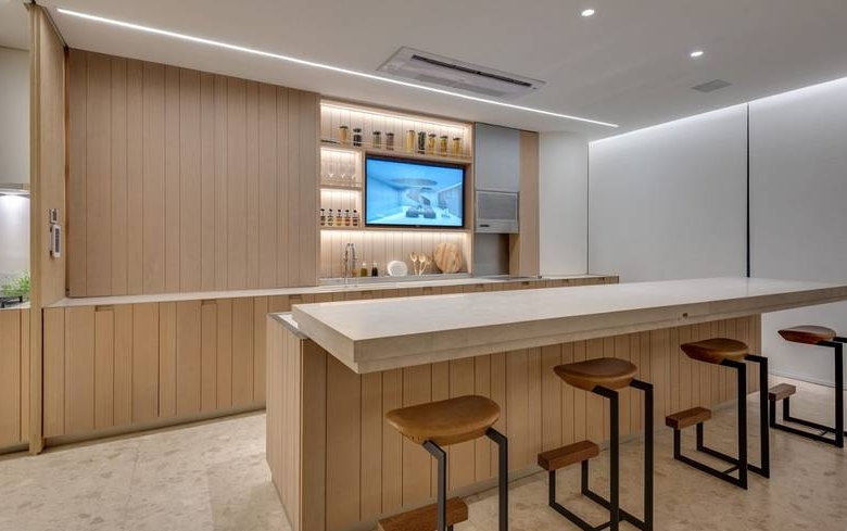 Sala de estar com mesa e cadeiras, além de iluminação embutida e revestimento claro