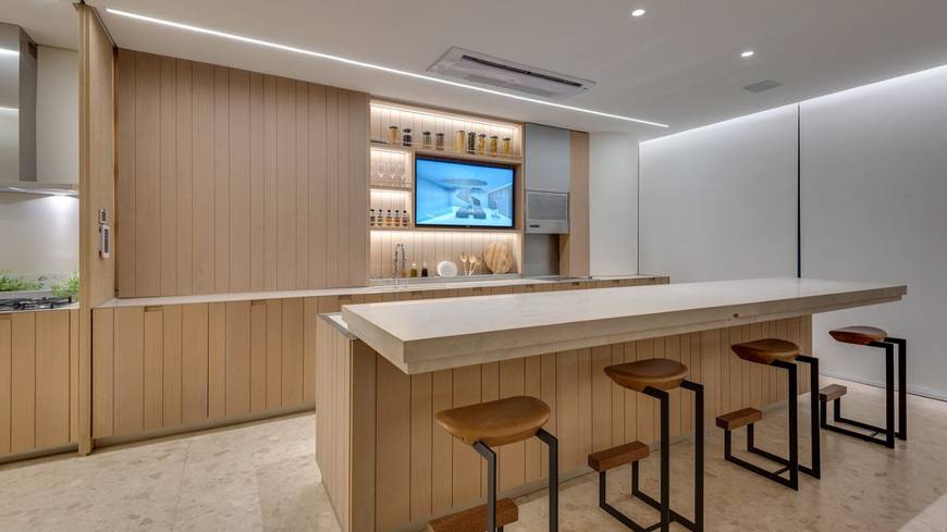 Sala de estar com mesa e cadeiras, além de iluminação embutida e revestimento claro