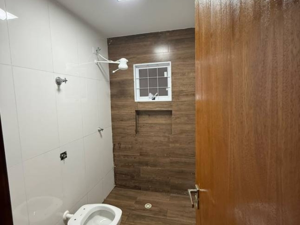 Banheiro com pia e espelho, além de revestimento de madeira no Casa no Setor Sudoeste, Goiânia