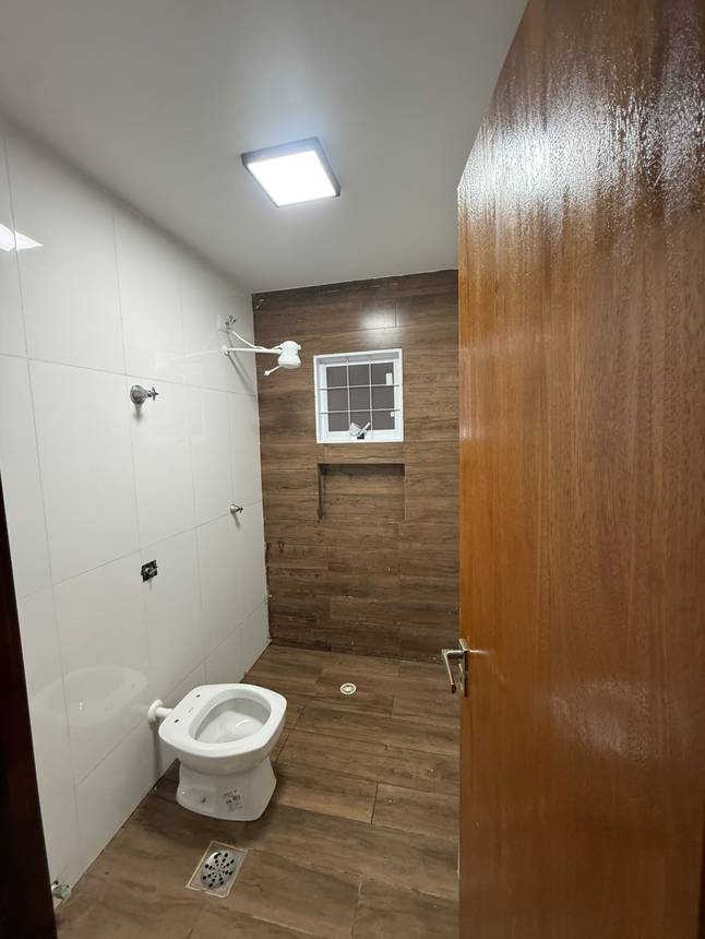 Banheiro com pia e espelho, além de revestimento de madeira no Casa no Setor Sudoeste, Goiânia