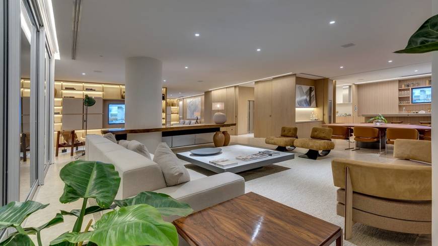 Sala de estar com sofá e televisão, além de iluminação embutida
