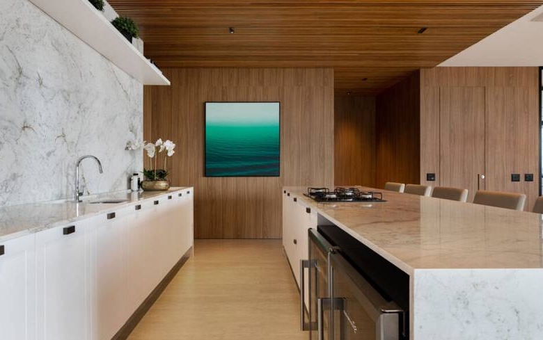 Cozinha com mesa de jantar, além de iluminação embutida e revestimento de madeira