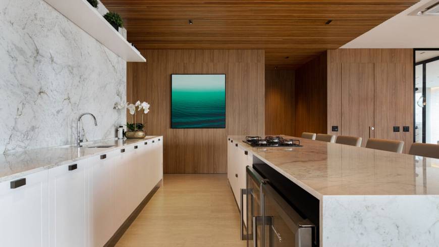 Cozinha com mesa de jantar, além de iluminação embutida e revestimento de madeira
