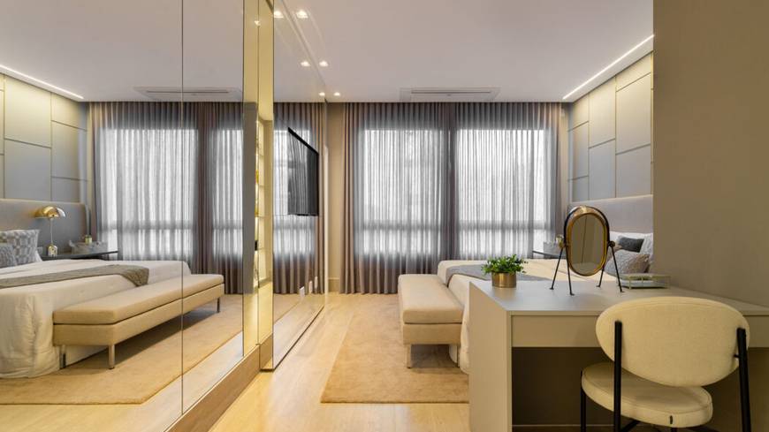 Ambiente interno com cama, espelho e luminária, além de iluminação embutida