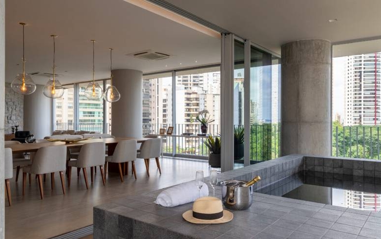 Sala de estar com mesa e cadeiras, além de iluminação embutida e revestimento claro