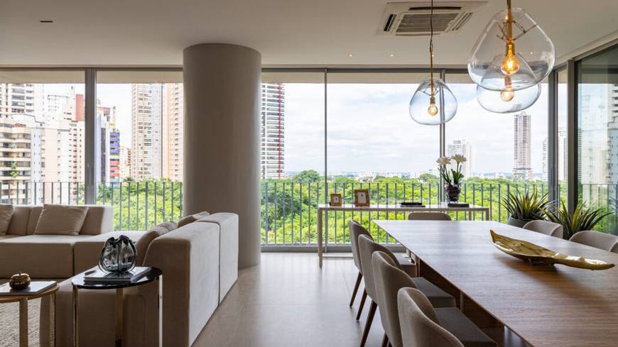 Sala de estar com sofá e mesa, além de iluminação embutida e revestimento claro