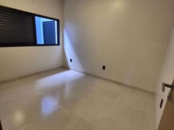 Quarto com piso claro, janela e iluminação no teto em casa moderna no bairro Alto Umuarama, em Uberlândia, Minas Gerais.