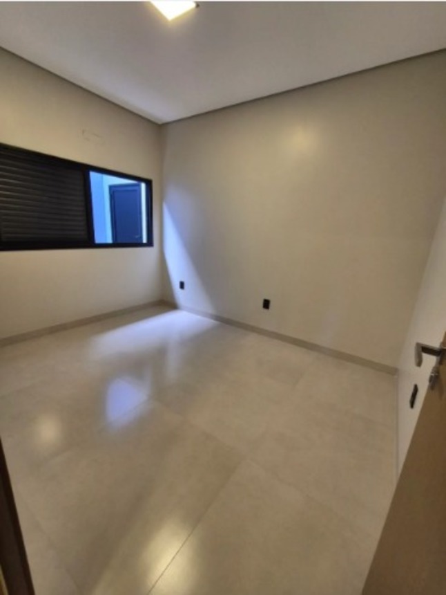 Quarto com piso claro, janela e iluminação no teto em casa moderna no bairro Alto Umuarama, em Uberlândia, Minas Gerais.