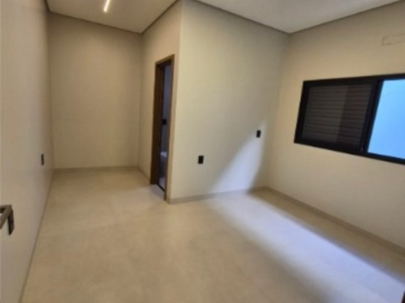 Quarto amplo com janela, piso claro e iluminação moderna no teto em casa no bairro Alto Umuarama, Uberlândia, Minas Gerais.