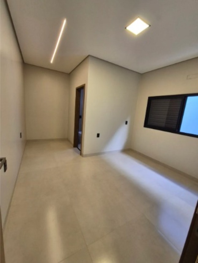 Quarto amplo com janela, piso claro e iluminação moderna no teto em casa no bairro Alto Umuarama, Uberlândia, Minas Gerais.