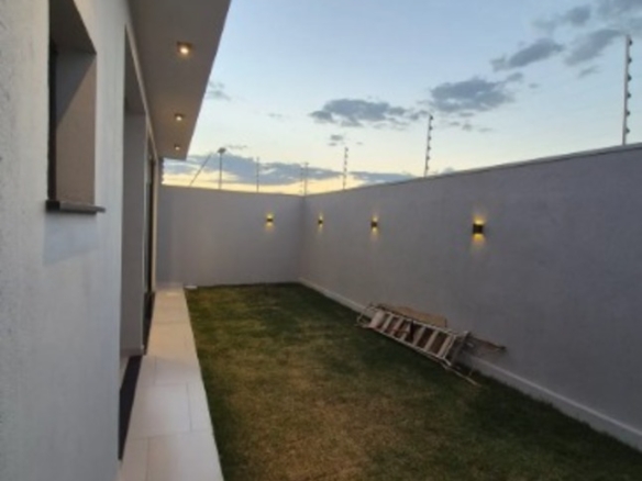 Quintal com gramado, muro alto e corredor lateral de casa no bairro Alto Umuarama, em Uberlândia, Minas Gerais.