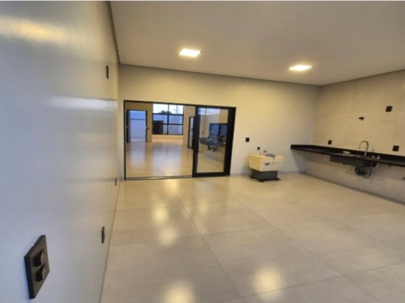 Sala ampla integrada à cozinha com bancada e iluminação embutida em casa no Alto Umuarama, Uberlândia, Minas Gerais.