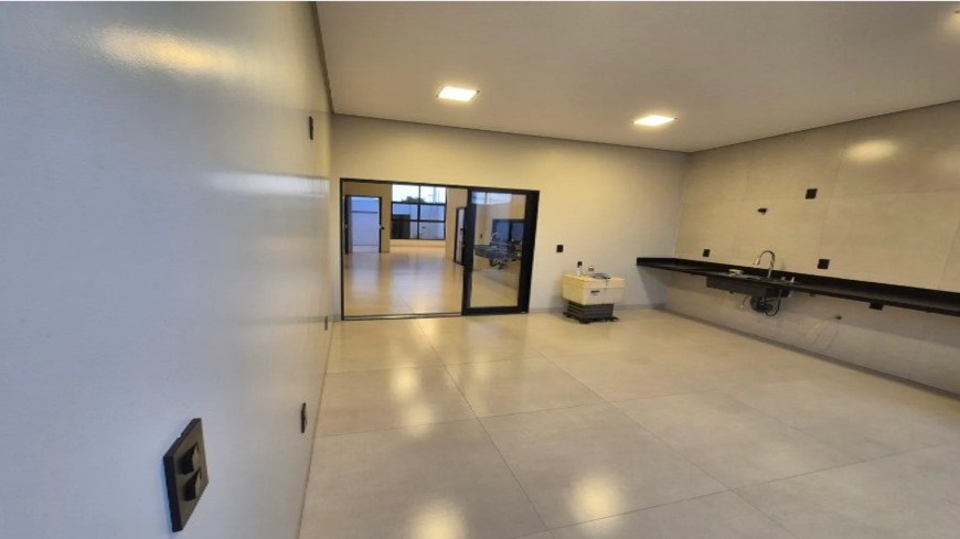 Sala ampla integrada à cozinha com bancada e iluminação embutida em casa no Alto Umuarama, Uberlândia, Minas Gerais.