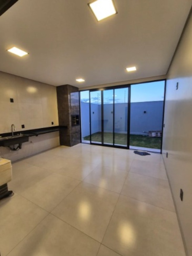 Sala de estar integrada à cozinha e quintal, com portas de vidro, em casa no Alto Umuarama, Uberlândia, Minas Gerais.