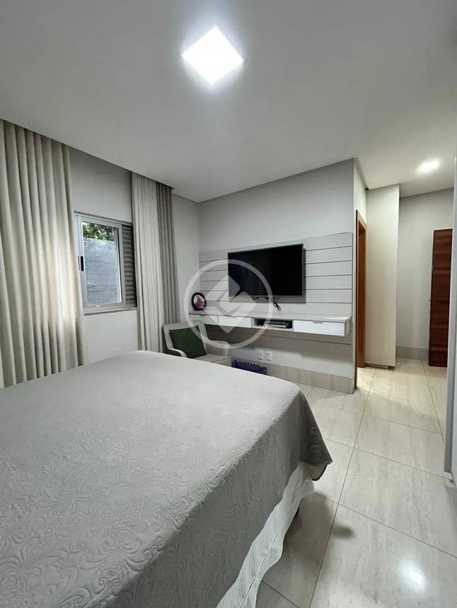 Sala de estar com painel de televisão, luminária e tapete