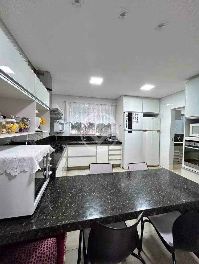 Cozinha com mesa de jantar e cadeiras, além de iluminação embutida e revestimento de madeira