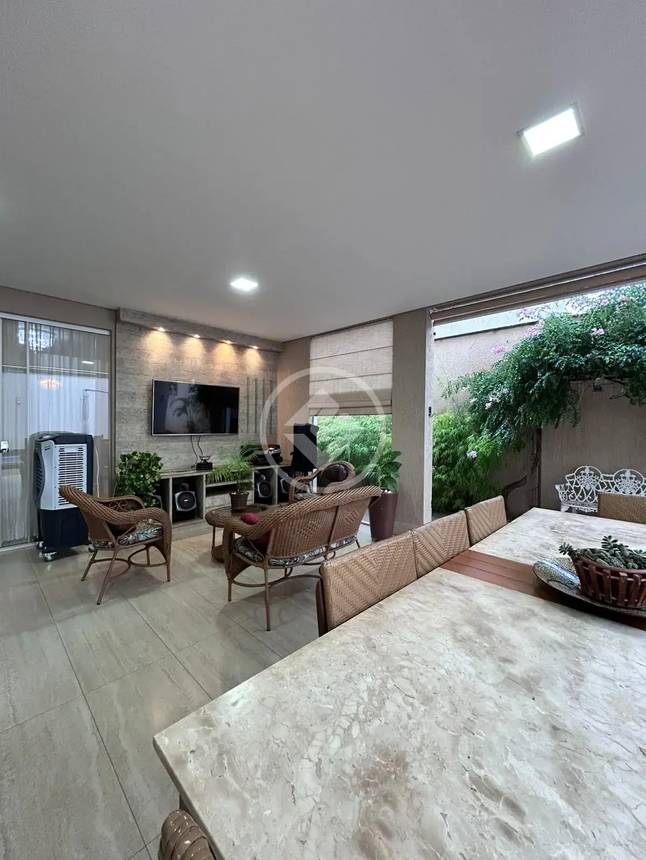 Sala de estar com mesa, cadeiras e televisão, além de iluminação embutida e revestimento de madeira