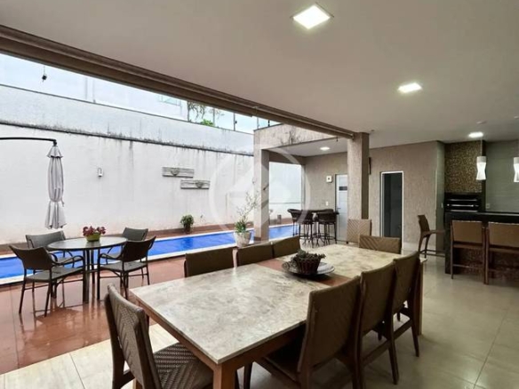 Sala de estar com mesa, cadeiras e luminária, além de iluminação embutida e piso de madeira