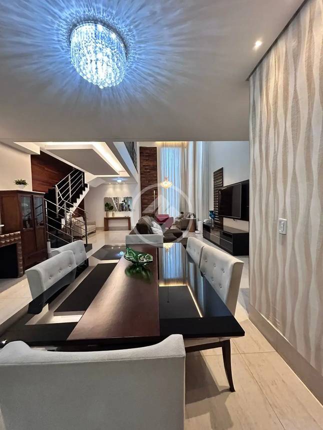 Sala de estar com mesa, cadeiras e luminária, além de iluminação embutida e revestimento de madeira no Alphaville Araguaia