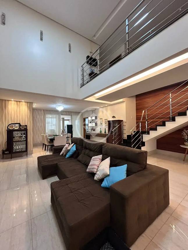 Sala de estar com sofá e mesa, além de iluminação embutida e revestimento claro