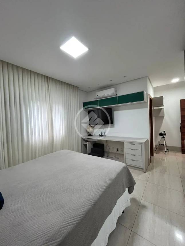 Sala de estar com painel de televisão, luminária e tapete, além de iluminação embutida