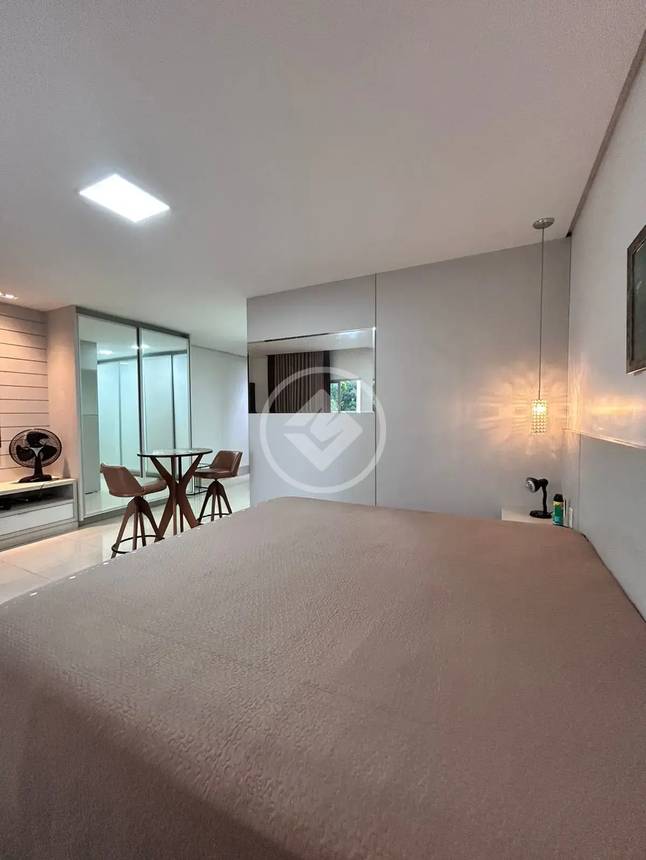 Sala de estar com mesa e luminária, além de iluminação embutida